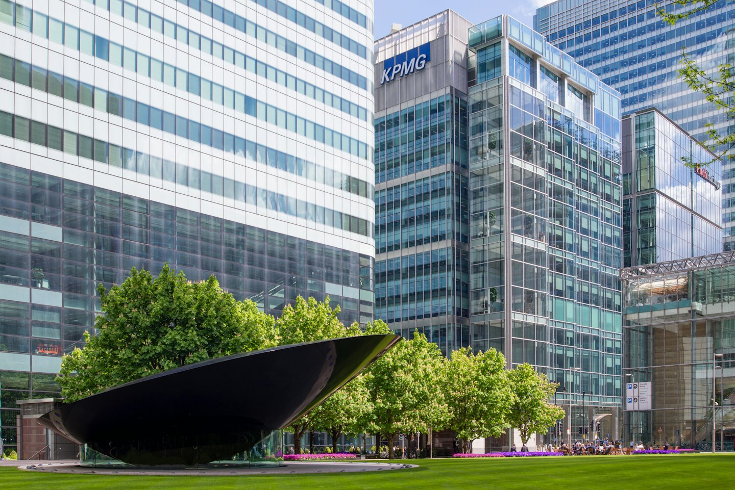 Modern corporate buildings reflect the sky above manicured green lawns.