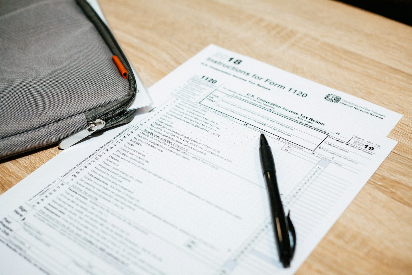 Two U.S. Corporation Income Tax Return Forms with a pen on a desk.